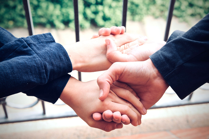 Fotografía de manos de piel blanca entrelazadas mostrando ternura