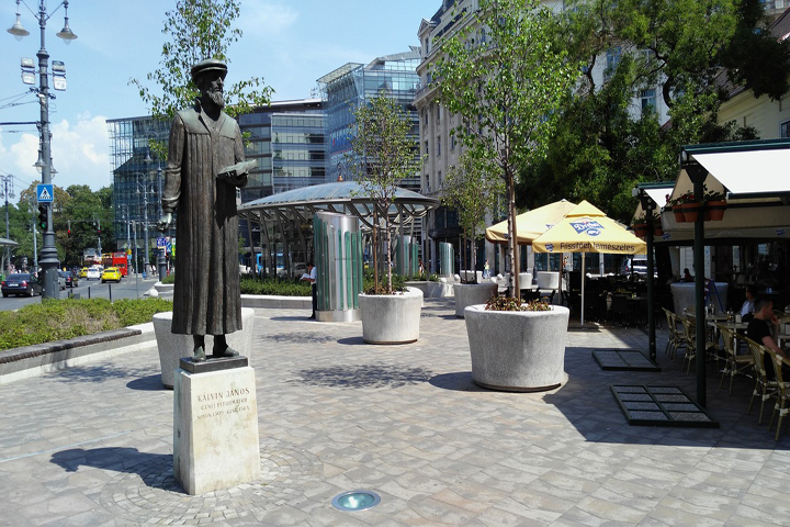 Plaza pública dedicada a Juan Calvino en Budapuest que muestra árboles alrededor y edificios al fondo
