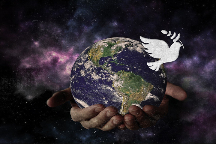 imagen del globo terráqueo sostenido por dos manos y en la esquina superior derecha una paloma que simboliza la paz